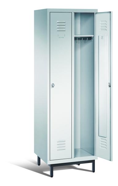 Ein lichtgrauer Garderobenschrank mit zwei Abteilen, zwei Fächern sowie integrierten Kleiderstangen mit Kleiderhaken, dessen rechte Tür geöffnet ist. Er steht auf Stahlrohrfüßen vor weißem Hintergrund.