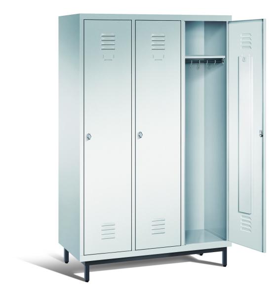 Ein lichtgrauer Garderobenschrank mit drei Abteilen, drei Fächern sowie integrierten Kleiderstangen mit Kleiderhaken, dessen rechte Tür geöffnet ist. Er steht auf Stahlrohrfüßen vor weißem Hintergrund.