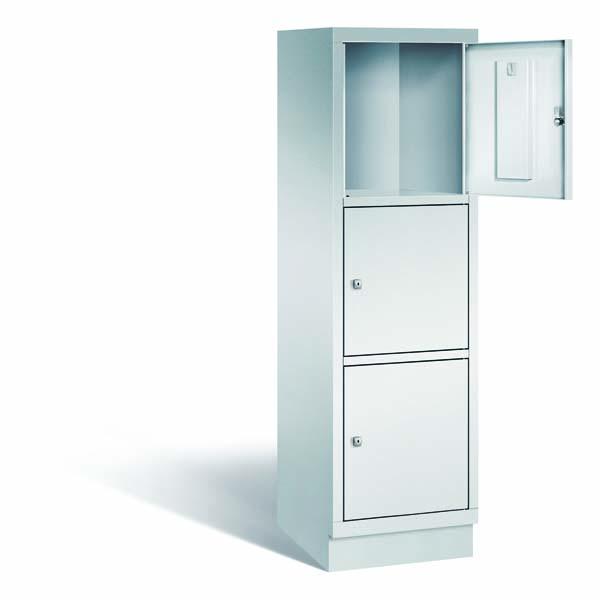 Ein lichtgrauer Fächerschrank mit einem Abteil, drei Türen und drei Fächern, ideal zur Aufbewahrung von Gegenständen. Die oberste der drei Türen steht offen und er steht vor einem weißen Hintergrund.