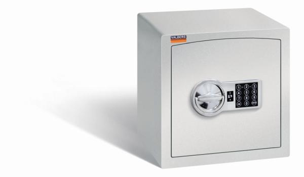 Ein lichtgrauer Möbeltresor mit einem elektronischen Schloss. Die Tür ist geschlossen. Der Tresor steht vor einem weißen Hintergrund.