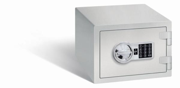 Ein lichtgrauer Möbeltresor mit einem elektronischen Schloss. Die Tür ist geschlossen. Der Tresor steht vor einem weißen Hintergrund.