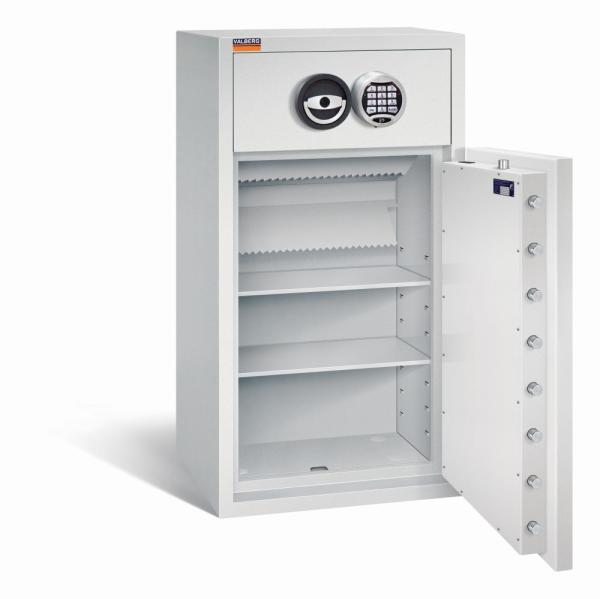 Ein lichtgrauer Deposittresor dessen Tür geöffnet ist. Im Türinnenraum befinden sich eine sichtbare Türverriegelung und ein Zertifikat. Der Innenraum ist leer und verfügt über zwei Fachböden. Der Tresor steht vor einem weißen Hintergrund